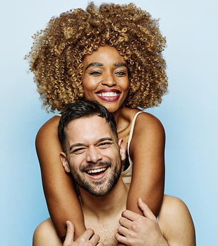 Healthy, Radiant Skin for Every Skin Type A smiling couple with healthy, glowing skin posing together against a soft blue background. The image represents inclusive aesthetic treatments, professional skin rejuvenation, and personalized skincare services for all skin types and tones.